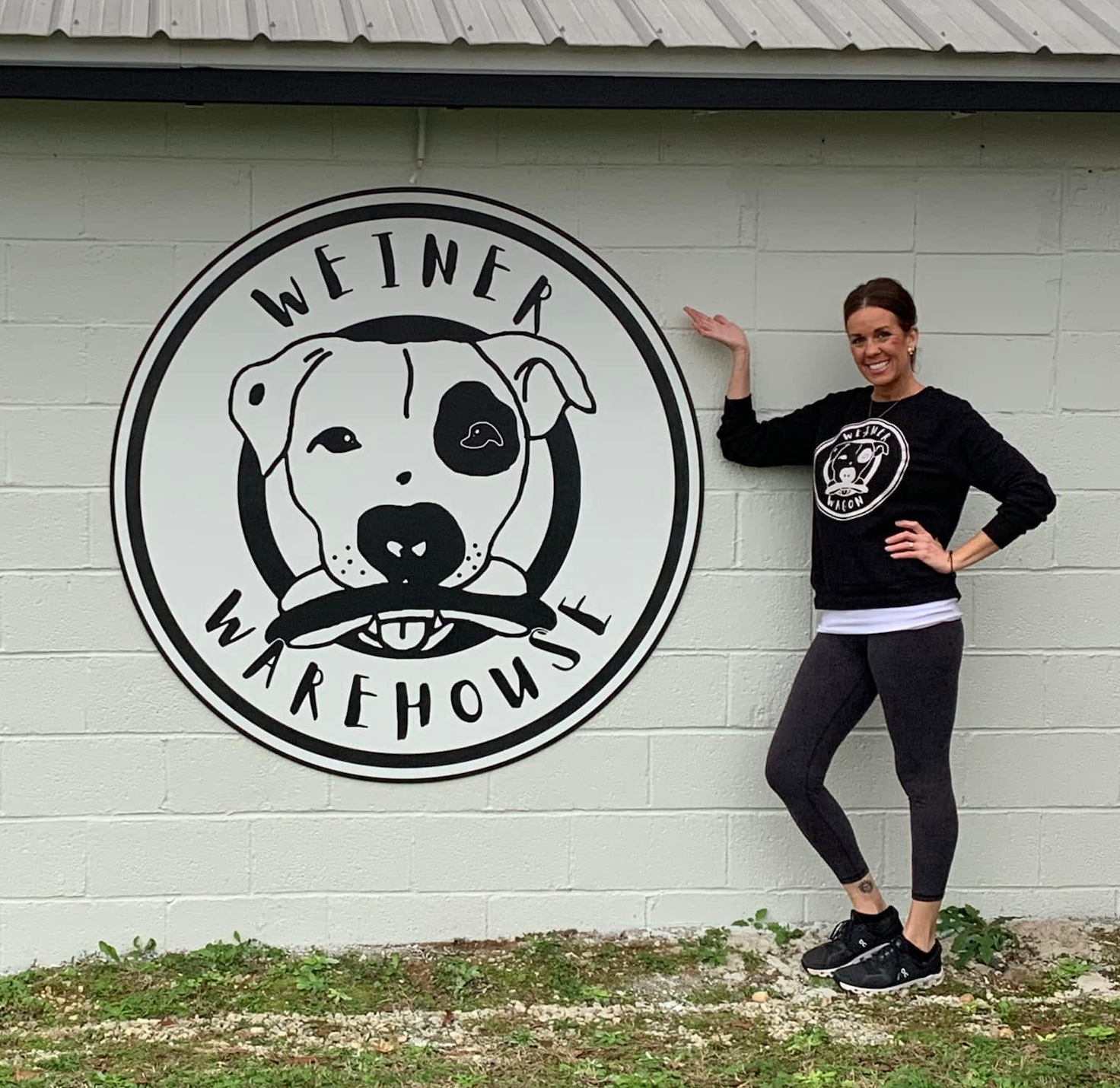 Christi Harpe standing next to the large Weiner Warehouse mural on the building wall
